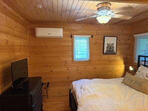 A wooden cabin bedroom with a bed, dresser, ceiling fan, and a framed picture on the wall. - Cozy Cabin Nestled on Infamous Ski Mountain Rd. (Gatlinburg)