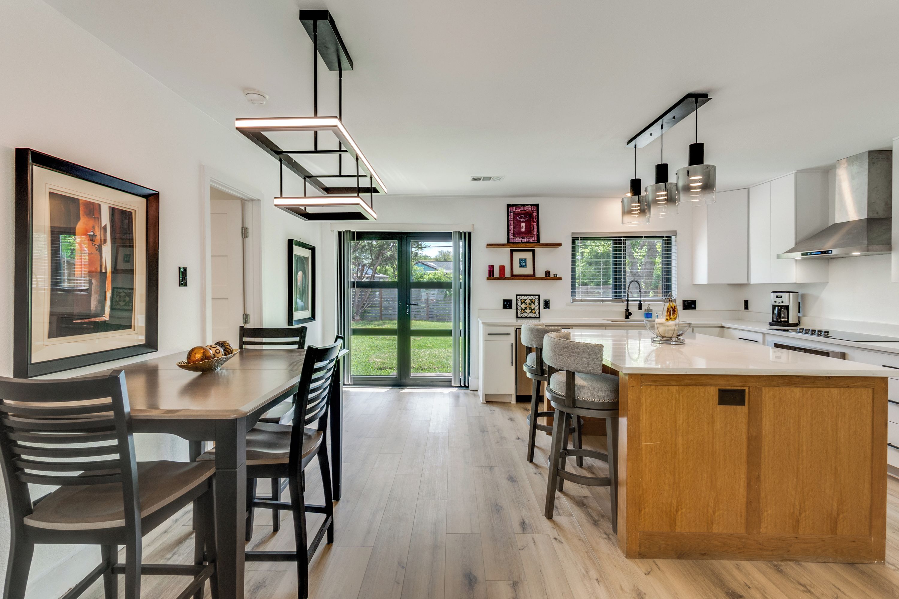 A modern kitchen with a central island, wooden chairs, and a dining table.