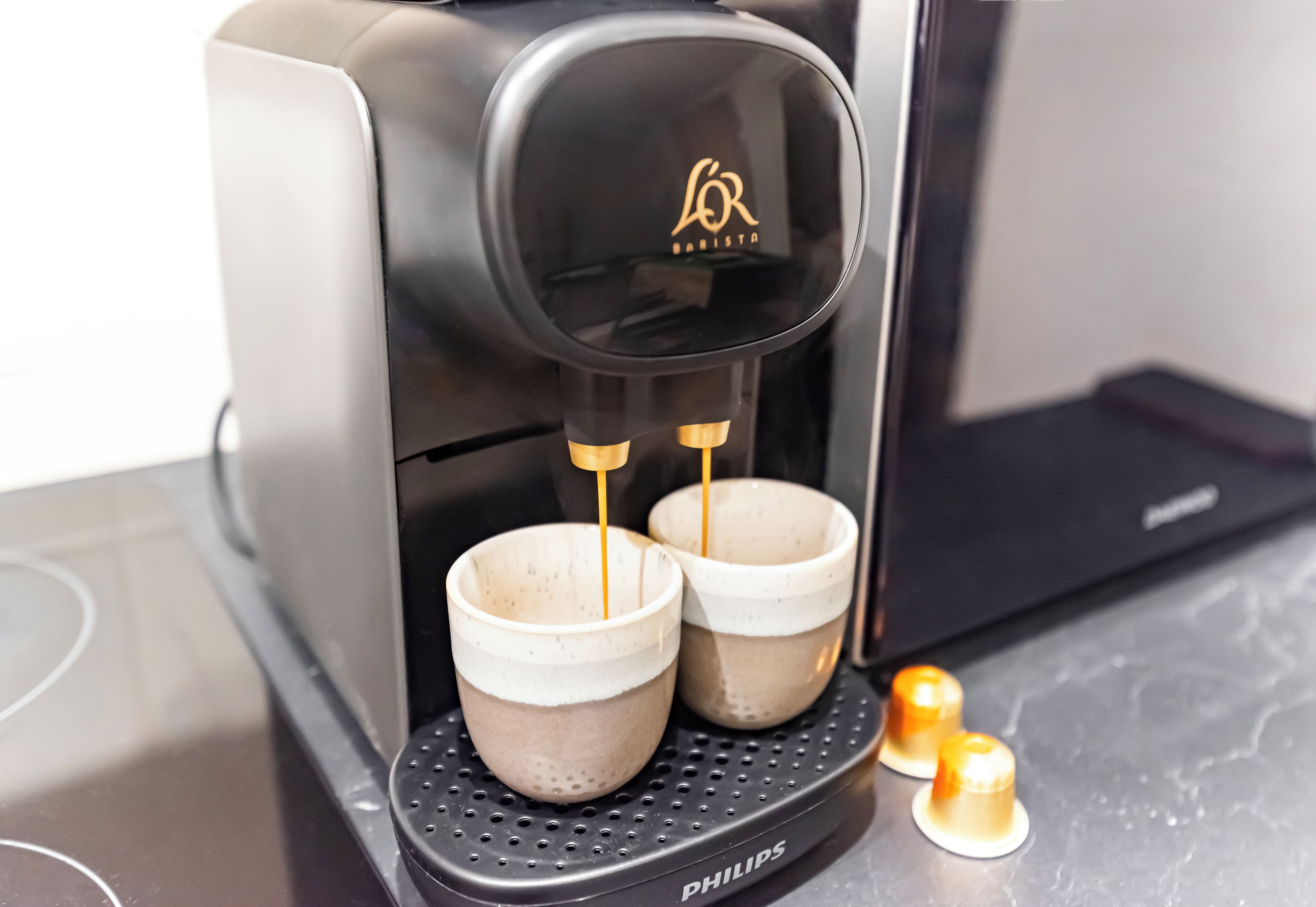 A coffee machine with two cups on its drip tray.