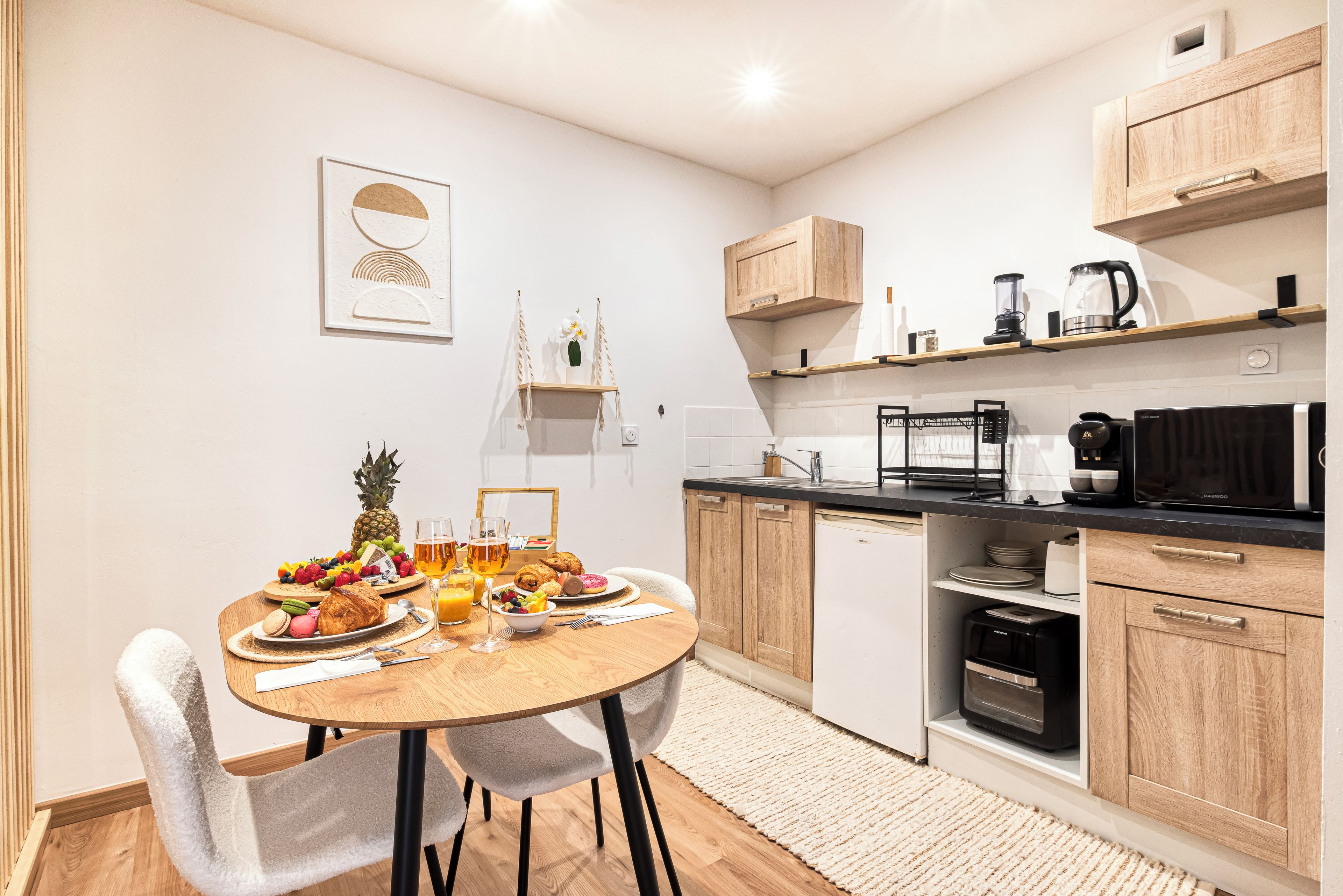 Een moderne keuken met houten kastjes, een eettafel met ontbijtproducten en een koffieapparaat.
