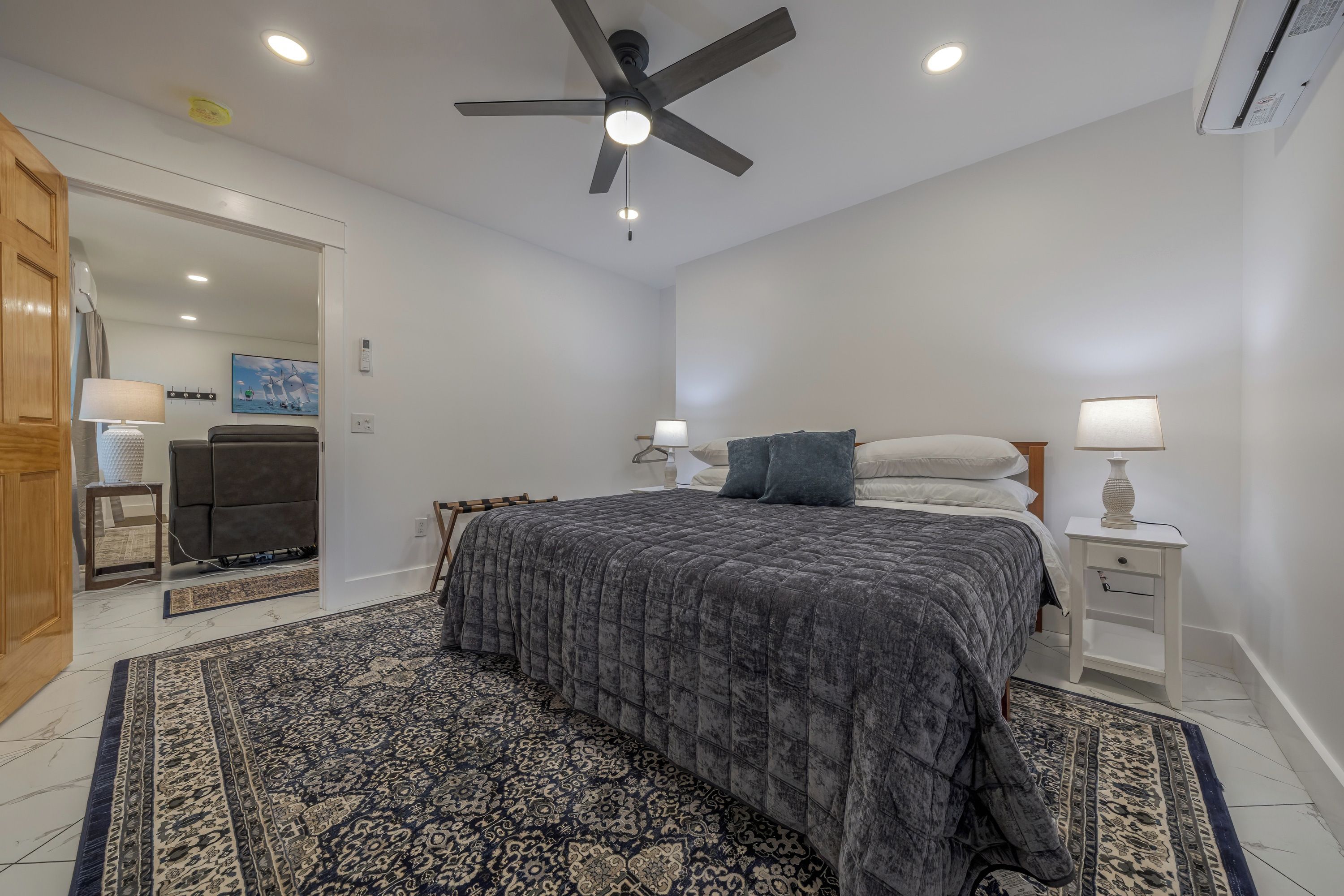 A bedroom with a bed, nightstands, a ceiling fan, and a patterned rug.