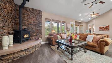 A living room with a stone wall, a fireplace, a brown sofa, and a glass coffee table.