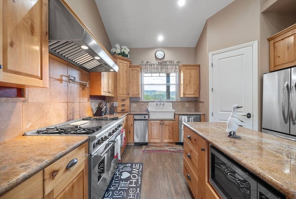 A kitchen with wooden cabinets, stainless steel appliances, and a view through the window.