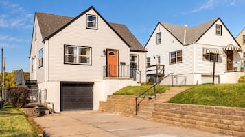 A residential area with two-story houses featuring front porches, a driveway, and a stone retaining wall.