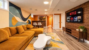 A modern living room with a sofa, coffee table, and a flat-screen TV displaying Netflix content.