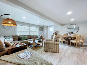 A spacious living room with a sofa, coffee table, and ottoman, a dining area with chairs and a table, and a ceiling with recessed lighting. - Casa LUNA,charming-newly remodeled 3BR/2BA Canalfront Retreat near Siesta Beach (Sarasota)