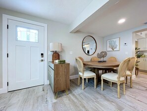 A dining area with a round table, six chairs, a lamp, a mirror, and a cabinet. - Casa LUNA,charming-newly remodeled 3BR/2BA Canalfront Retreat near Siesta Beach (Sarasota)