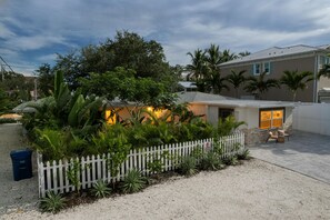 A residential property with a white picket fence, a gravel driveway, and a house with a visible garage door. - Casa LUNA,charming-newly remodeled 3BR/2BA Canalfront Retreat near Siesta Beach (Sarasota)