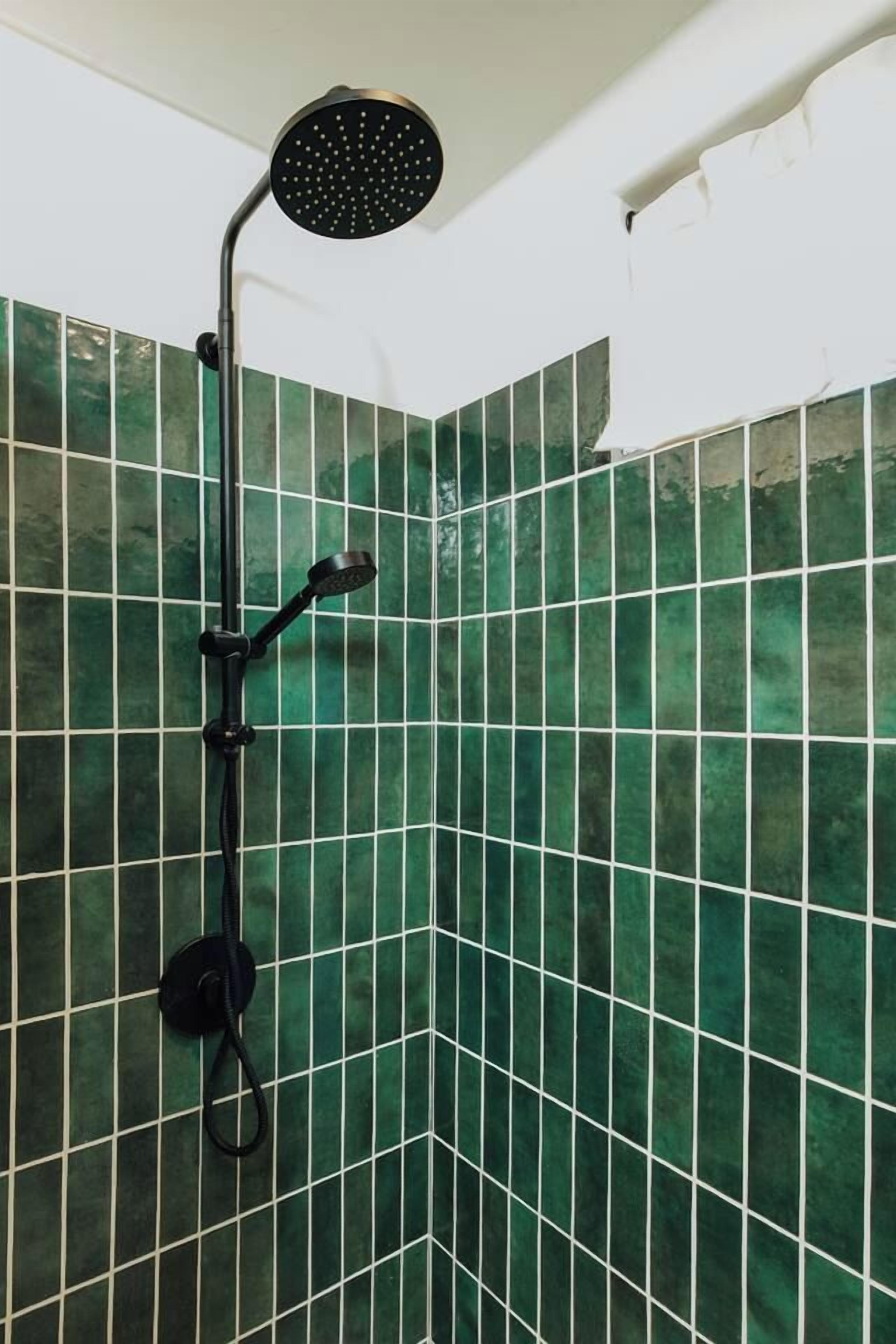 A shower with a handheld showerhead and a wall-mounted control.