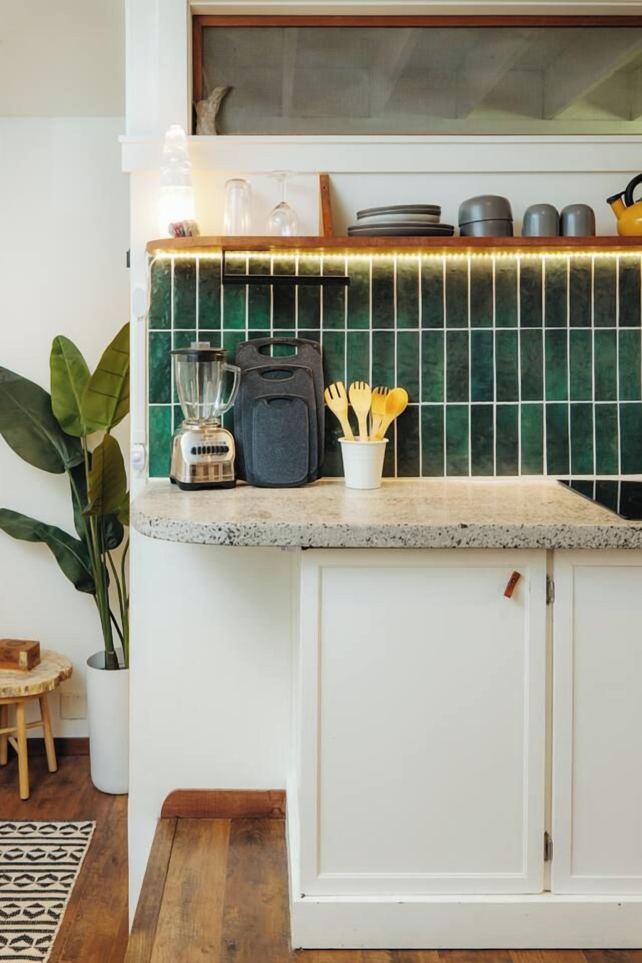 A kitchen with a granite countertop, a blender, a kettle, and a cup with utensils.