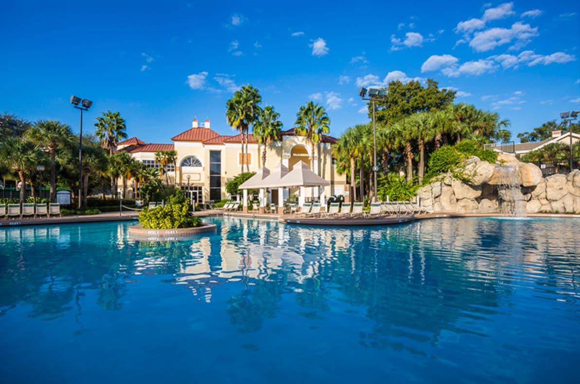 Ein Resort mit Schwimmbad, Palmen und einem Gebäude mit rotem Dach.