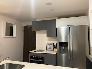 A modern kitchen with a stainless steel refrigerator, a built-in oven, and a coffee maker on the countertop. - Nunciatura King Bed | Pool + Parking | Ü Tower, San José, Costa Rica. (San José)