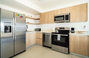 Une cuisine moderne dotée d’appareils électroménagers en acier inoxydable, de meubles en bois et d’un four à micro-ondes encastré.
