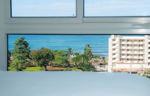A view of a coastal area with a building and trees. - Live Jaco 1207 Ocean View 2BR Condo Near Beach (Jaco)