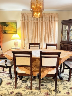 A dining room with a table, chairs, a chandelier, curtains, a lamp, and a cabinet. - Cozy Home in Serene Orange walking distance to town! (Orange)