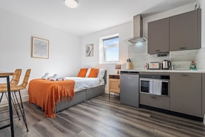 A compact kitchen with a dishwasher, a coffee maker, and a kettle. - Sutherland Apartments - Apt 26 (London)