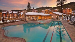 Ein Resort mit Schwimmbad, Liegestühlen und Gebäuden mit schneebedeckten Dächern.
