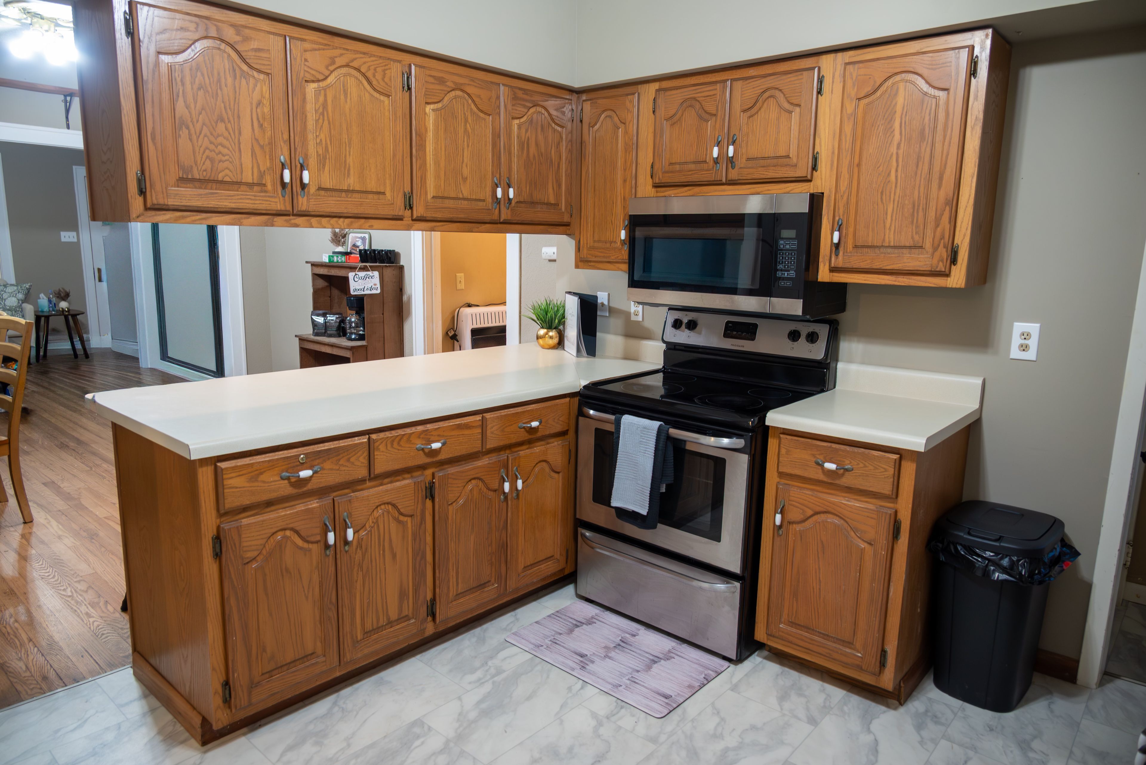 Una cocina con armarios de madera, estufa de acero inoxidable y microondas.