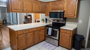 Una cocina con armarios de madera, estufa de acero inoxidable y microondas.