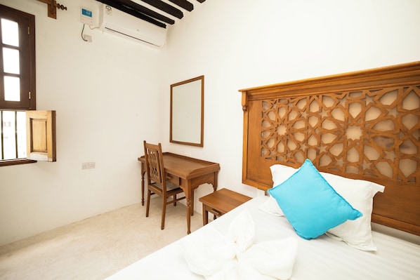 A bedroom with a bed, a wooden headboard, a desk, and a chair.