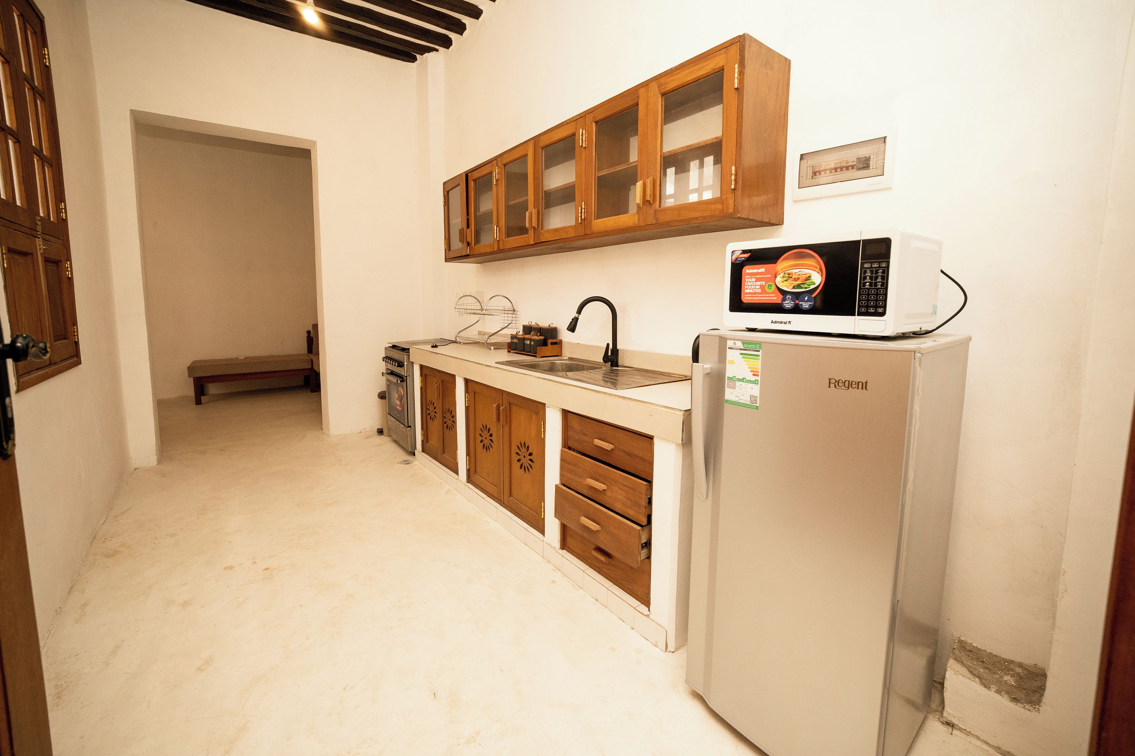 A compact kitchen with wooden cabinets, a white refrigerator, and a microwave.