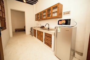 A compact kitchen with wooden cabinets, a white refrigerator, and a microwave.