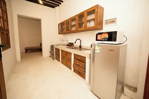 A compact kitchen with wooden cabinets, a white refrigerator, and a microwave.