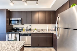 A modern kitchen with dark wood cabinets, stainless steel appliances, and a granite countertop. - Relax near PHX DT Gym Balcony Pool Parking WD (Phoenix)