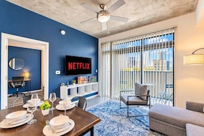 A modern living room with a dining area, a flat-screen TV, and a balcony with a city view. - Relax near PHX DT Gym Balcony Pool Parking WD (Phoenix)