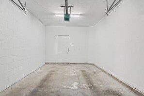 Ein Zimmer mit weißen Backsteinwänden, einem Betonboden, einer Tür und Neonbeleuchtung.