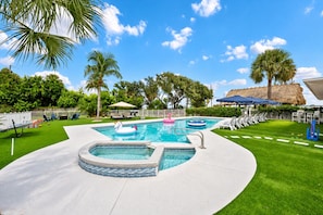 A swimming pool with a hot tub, lounge chairs, and palm trees. - The Conchy Cabana- Unit 2 (Jensen Beach)