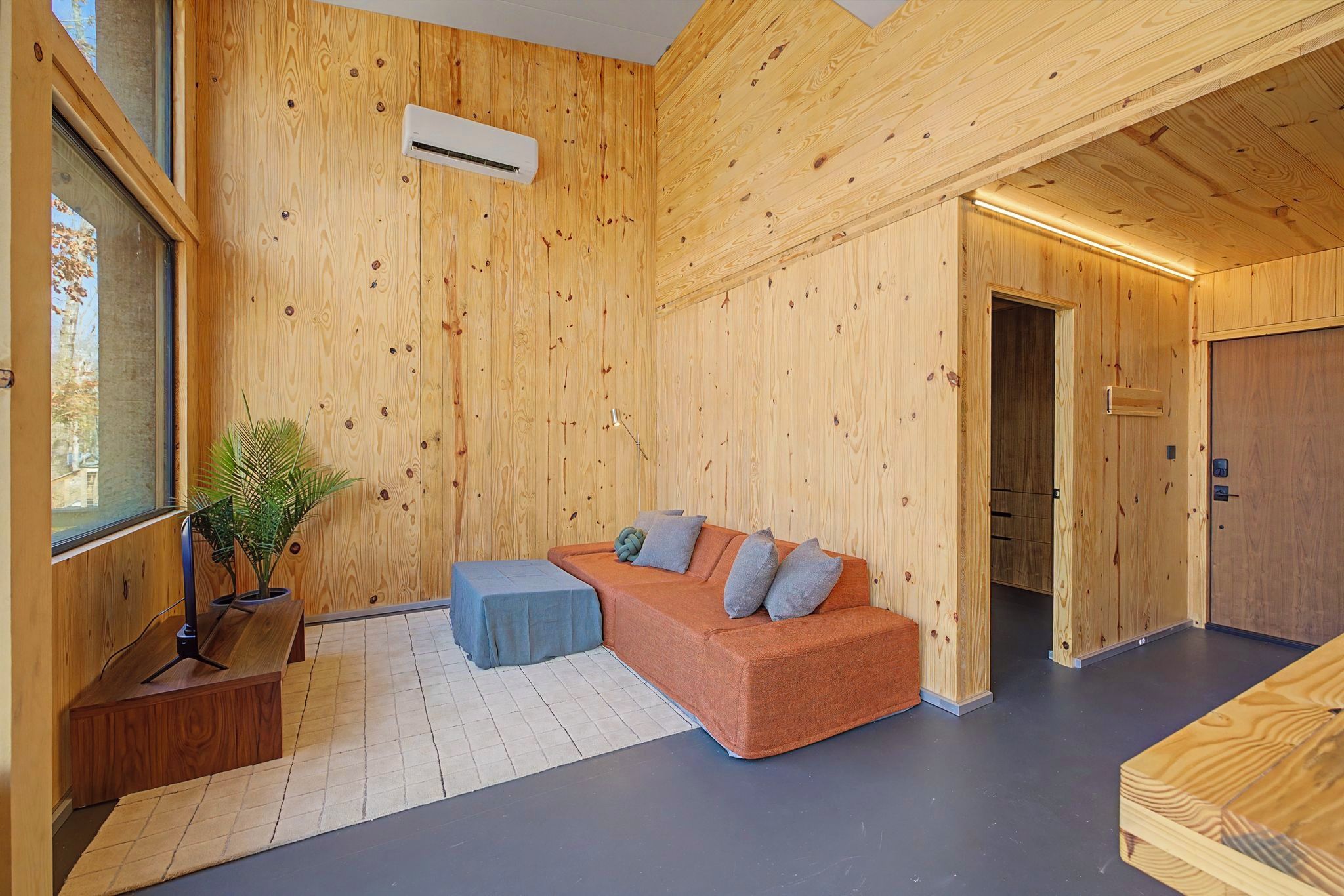 Een modern interieur met een houten wand, een bank, een klein tafeltje en een potplant.