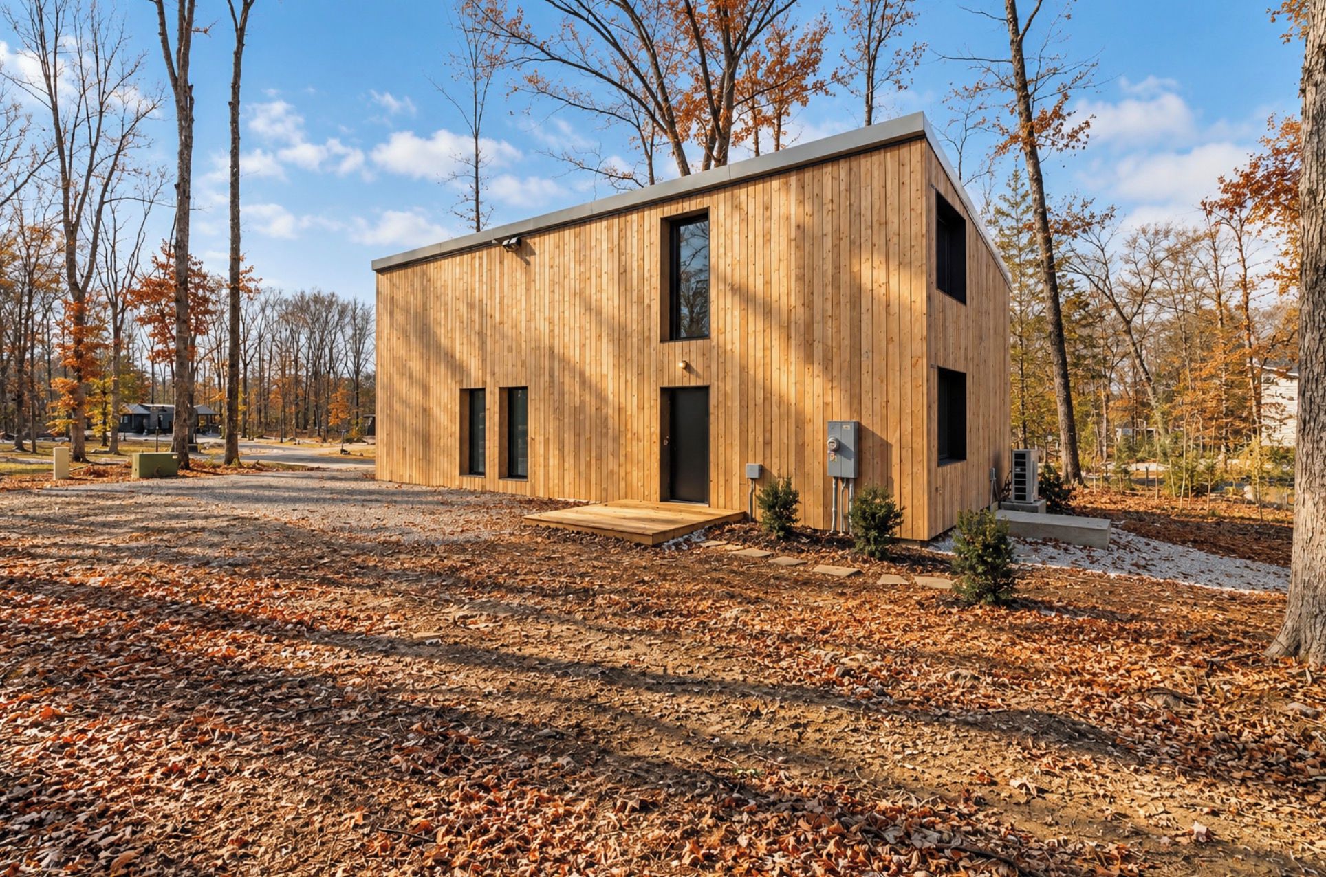 Une cabane moderne en bois, dotée d’un toit plat, de deux fenêtres apparentes et d’un petit porche.