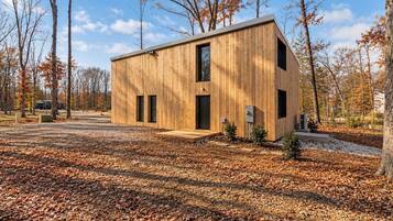 Une cabane moderne en bois, dotée d’un toit plat, de deux fenêtres apparentes et d’un petit porche.