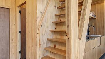 Un escalier en bois avec un coin cuisine en bas, comprenant un évier et des placards.