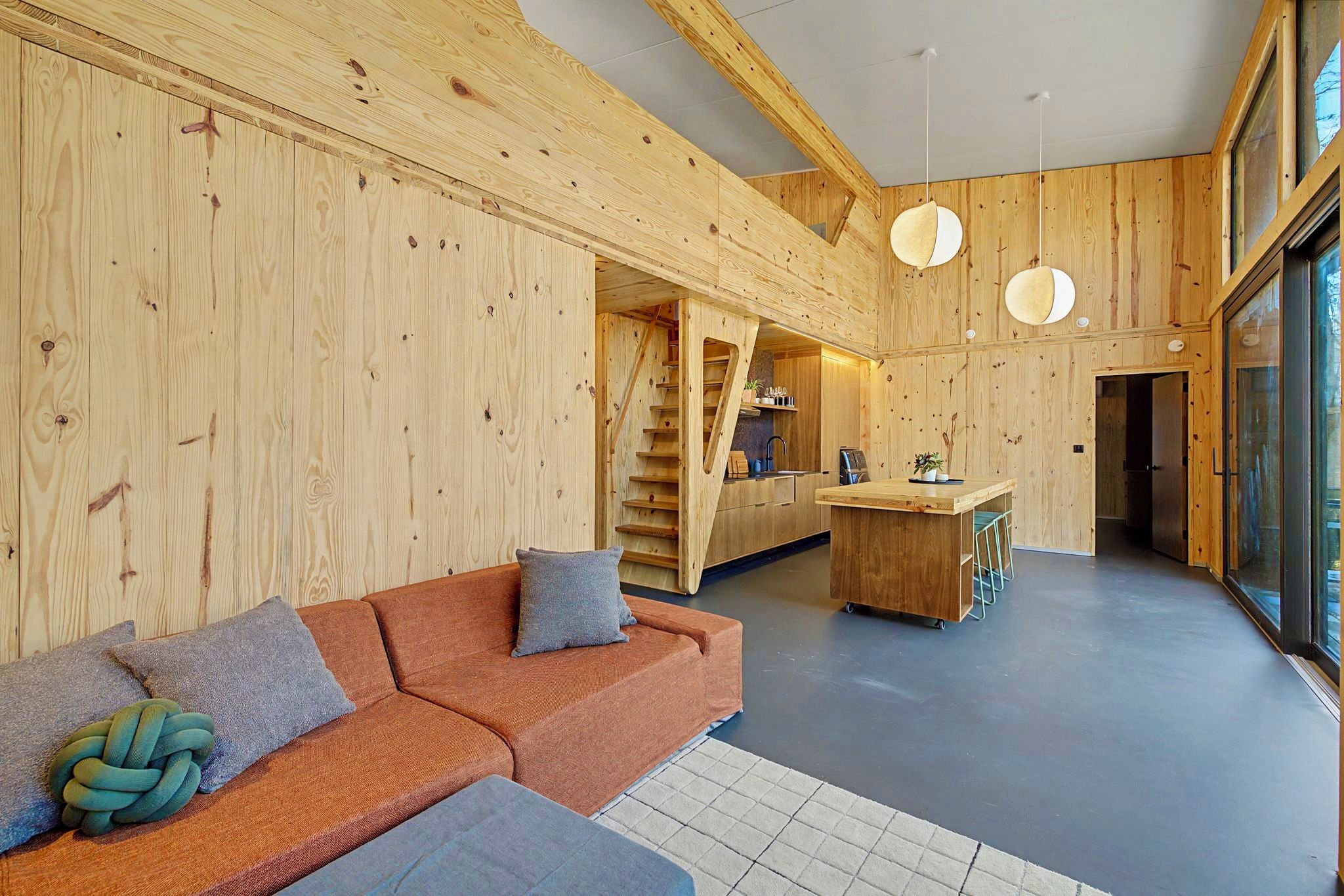 Un intérieur moderne avec un mur en bois, un canapé, un coin cuisine et un escalier.