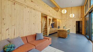 Un intérieur moderne avec un mur en bois, un canapé, un coin cuisine et un escalier.