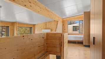 A modern interior with wooden walls and floors, a bench, and a window providing a view.