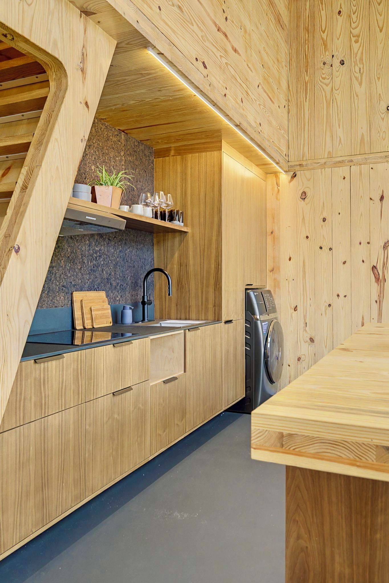 Une cuisine moderne avec des meubles de rangement en bois, un évier encastré et un lave-linge.