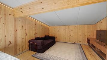Une pièce aux murs en bois, avec un canapé sombre, un meuble pour la télévision et un tapis à motifs.