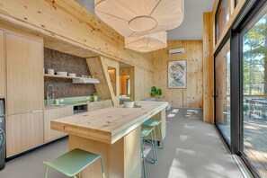 Een moderne keuken met een centraal eiland, barkrukken en een groot raam.