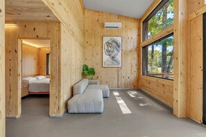 Ein modernes Interieur mit Holzwänden, einem großen Fenster, einer Couch und einem gerahmten Kunstwerk.