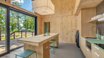 Una cocina moderna con una isla de madera, taburetes de bar, horno empotrado y vistas al exterior.