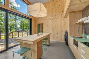 Een moderne keuken met een houten kookeiland, barkrukken, een inbouwoven en uitzicht op het groen.