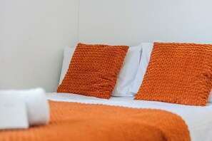 A bed with white bedding and two orange pillows. - Sutherland Apartments - Apt 27 (London)