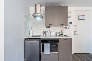 A compact kitchen with a dishwasher, oven, and a coffee maker. - Sutherland Apartments - Apt 27 (London)