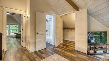 A spacious room with wooden flooring, a television, and a bookshelf.