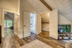 A spacious room with wooden flooring, a television, and a bookshelf. - Private Pool, Fenced Yard, Sauna, Hot Tub & Outdoor Fireplace | 5 Min downtown (Ellijay)