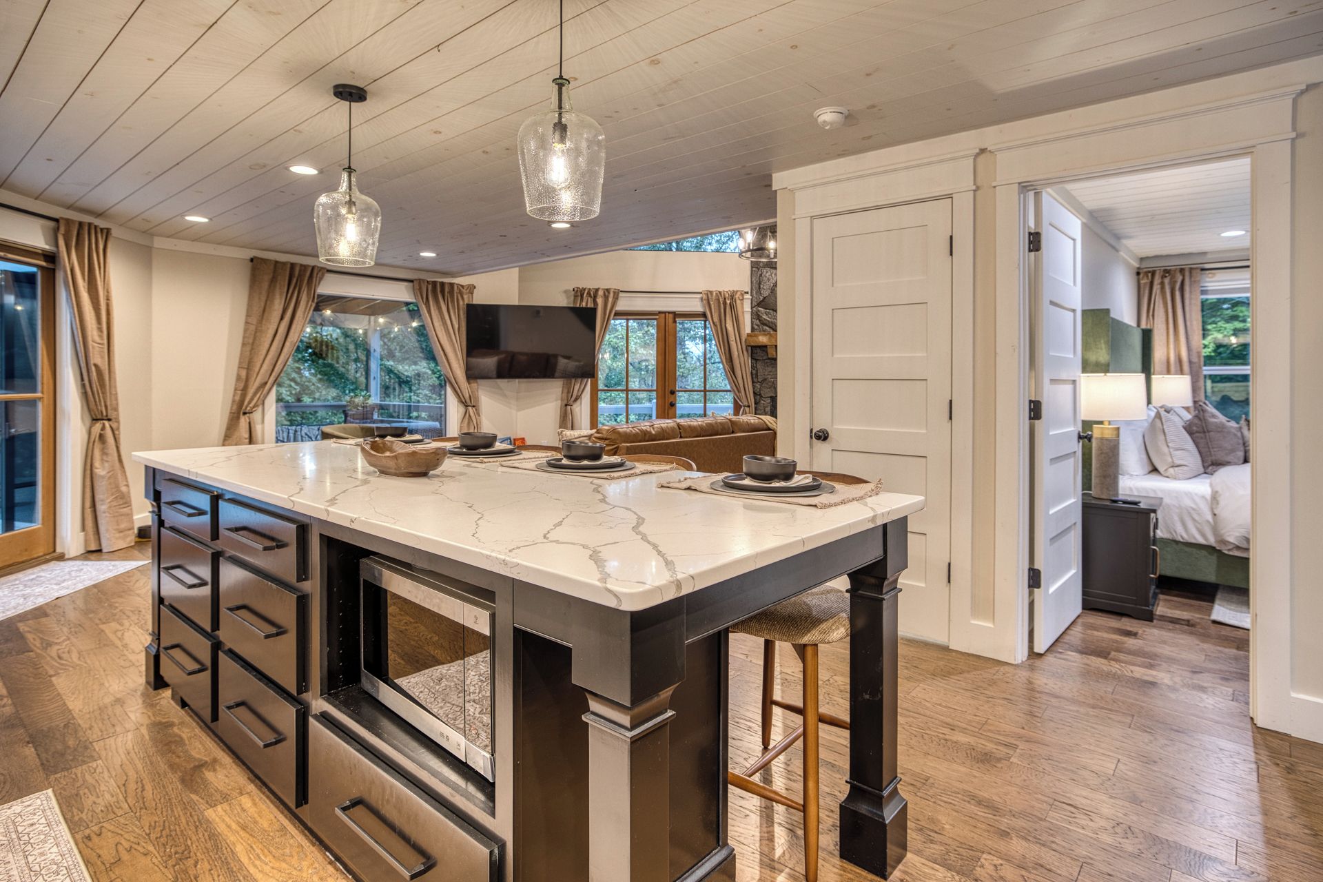 A kitchen with a marble island, wooden cabinets, and pendant lighting.