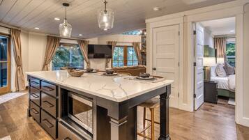 A kitchen with a marble island, wooden cabinets, and pendant lighting.